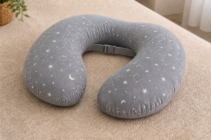 Representative image of a medium-grey U-shaped nursing support pillow with a white celestial-patterned cotton cover and fastening strap; actual product appearance may vary.